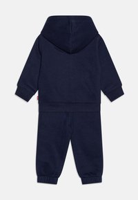 Navy blue two-piece tracksuit featuring a hooded sweatshirt and tapered pants with ribbed cuffs, made from soft fabric for comfort.