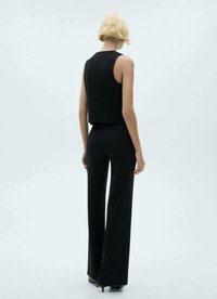 Svart ärmlös topp med en åtsittande design, i kombination med högmidjade vida byxor. Slät tygkvalitet och minimalistisk estetik genomgående.