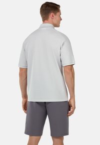Polo shirt grigio chiaro con maniche corte, texture liscia e colletto sottile. Abbinato a pantaloni corti grigio scuro, entrambi dal design casual.