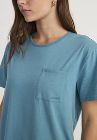 Lichtblauwe t-shirt met korte mouwen, gemaakt van zachte katoen, met een borstzakje waarin het JOCKEY-logo geborduurd is. Geribbelde halslijn en een ontspannen pasvorm.