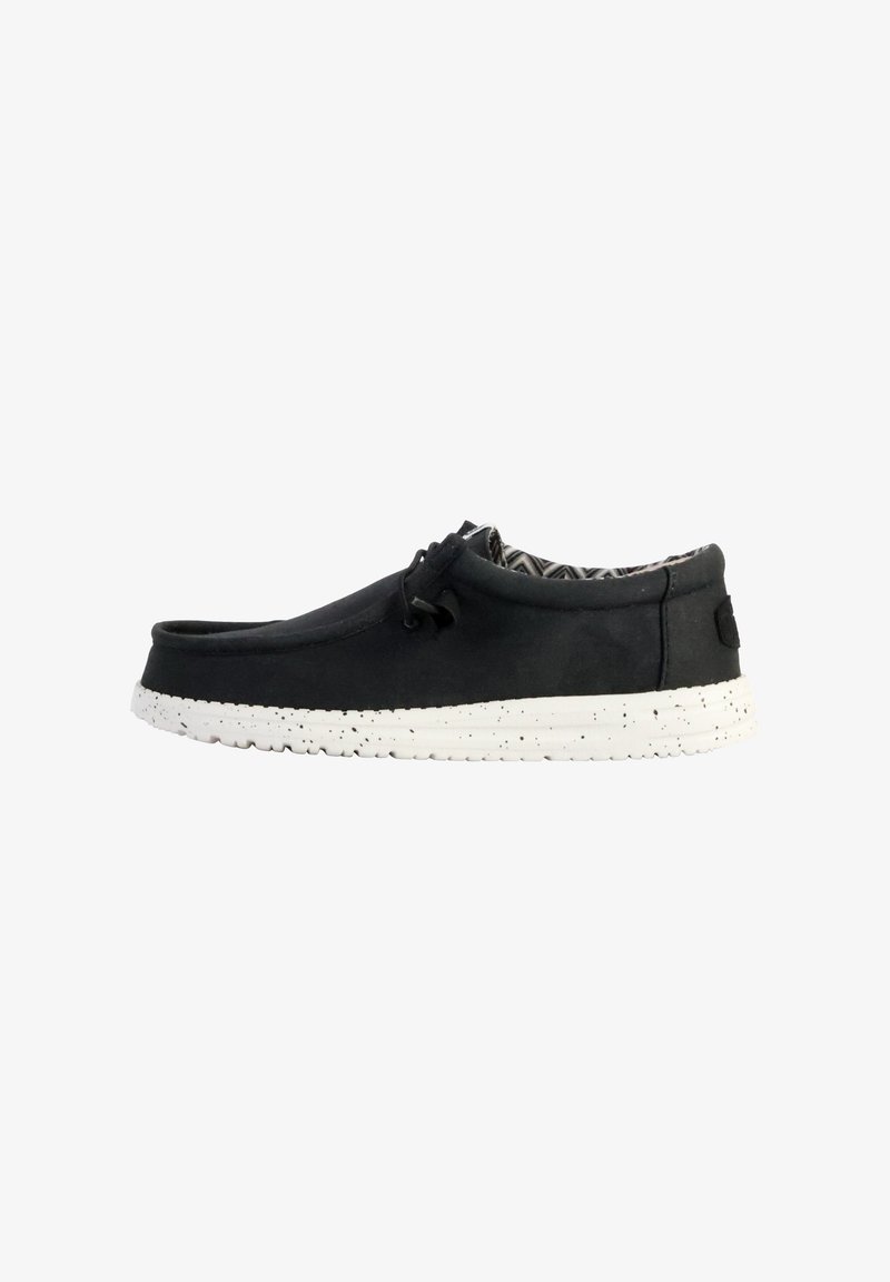 Scarpa nera slip-on con tomaia texture, suola in gomma bianca maculata e fodera interna a motivo. Lacci per regolazione.