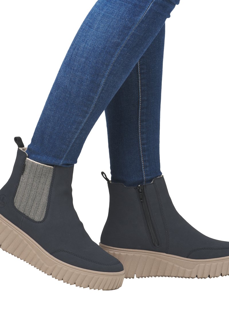 Bottines noires avec des côtés élastiques et une fermeture éclair, dotées d'une semelle en plateforme beige texturée et d'un accent en chevrons.