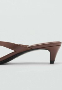 Braune Sandalen mit Absatz in einem eleganten Design, aus glattem Leder gefertigt, mit überkreuzten Riemen und einem niedrigen Blockabsatz für Stabilität.