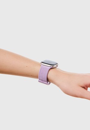 Smartwatch mit silbernem Gehäuse und lavendelfarbenem geflochtenem Armband am linken Handgelenk vor einem hellgrauen Hintergrund.