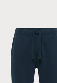 Mørkeblå sweats i blødt stof, med justerbar snøre i taljen og sidelommer for funktionalitet. Glat overflade.