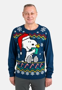 Sweater features a navy blue knit with a festive Snoopy design. Accents include snowflakes, candy canes, and a red Santa hat.