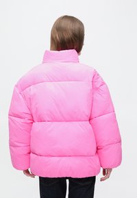 Ružová nadýchaná bunda s vysokým golierom, hranatým strihom, prešívaným dizajnom a dlhými rukávmi. Jednofarebná bez viditeľných vzorov alebo ozdôb.