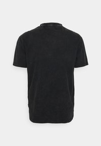 T-shirt en coton noir avec un col rond, des manches courtes et une finition légèrement texturée et délavée. Présente des coutures contrastantes.