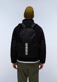 Černý batoh s hladkým povrchem, s výrazným bílým logem, nastavitelnými popruhy a síťovými bočními kapsami, nošený na osobě.