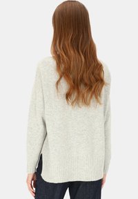 Jasnoszary, oversize sweter z miękkiego dzianego materiału, z prążkowanym dołem i bocznymi rozcięciami, wyposażony w długie rękawy i luźny fason.