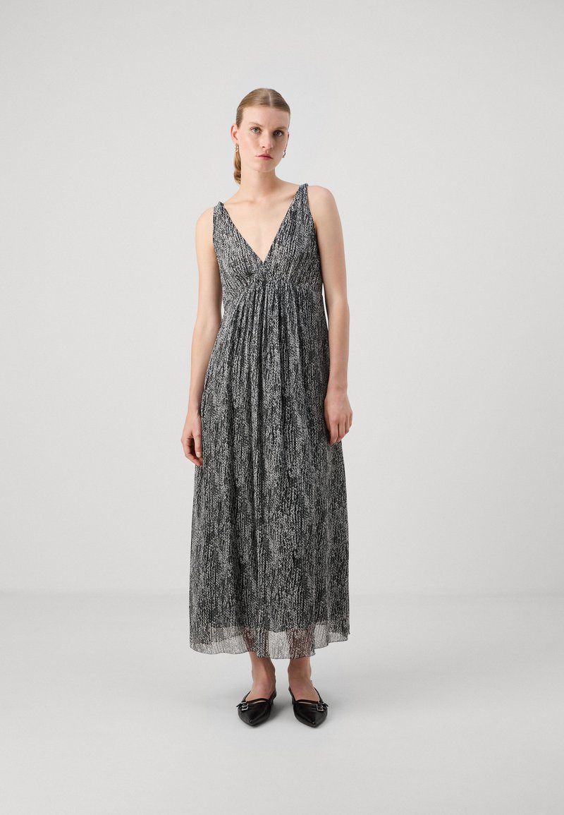 Robe maxi à motif noir et blanc avec un décolleté en V profond, en tissu léger et taille froncée, associée à des ballerines noires pointues.