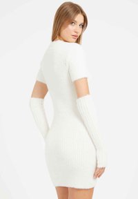 Balta prigludusi suknelė su trumpomis rankovėmis ir mezginiais. Yra ilgų rankų šildytuvų ir tekstūruotto, švelnaus audinio su gyslotu raštu.