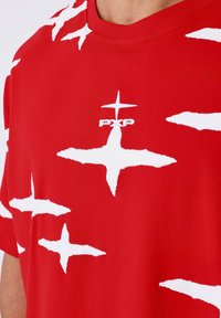 Rode katoenen t-shirt met een gedurfde witte stervormige patroon en een klein "PXP" logo in het midden van de borst. Standaard ronde halslijn.
