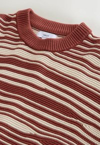 Gestrickter Pullover mit rundem Halsausschnitt, versehen mit einem roten und cremefarbenen Streifenmuster. Strukturierter Stoff mit lässiger Passform und geripptem Kragen.