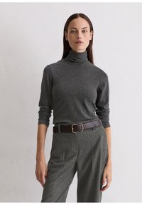 Grauer Rollkragenpullover mit langen Ärmeln, kombiniert mit hoch taillierten, gemusterten grauen Hosen und einem dunkelbraunen Gürtel mit einer goldenen Schnalle.