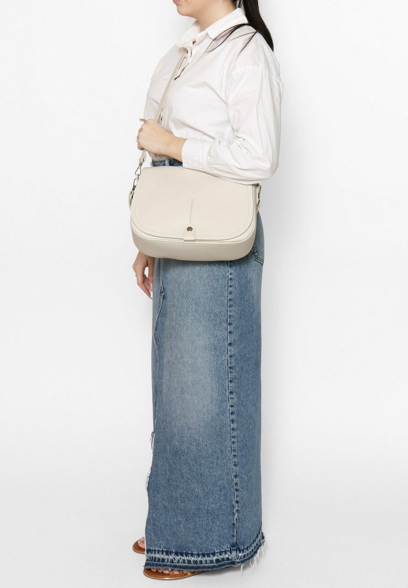 Sac bandoulière beige avec une texture lisse, de forme rectangulaire et une fermeture à rabat simple, doté d'une courte sangle ajustable.