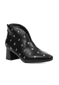 Botín de cuero negro hasta el tobillo con punta afilada, adornado con acentos de tachuelas plateadas y un tacón bajo cuadrado. Cierre con cremallera en el lateral.