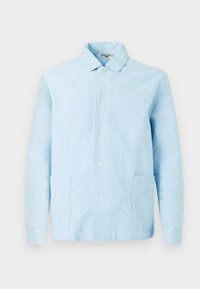 Lys blå, langermet skjorte laget av vevd stoff. Har krage, knappeåpning foran og to påsydde lommer. Glatt tekstur.