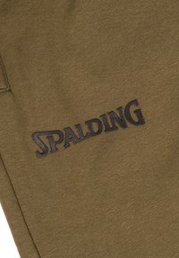 Olijfgroene stof met een gladde textuur; heeft een groot zwart "SPALDING" logo dat op het oppervlak is gedrukt.