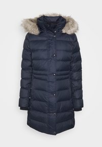 Abrigo acolchado azul marino con ribete de piel sintética en la capucha, cierres de presión, puños acanalados y costuras verticales decorativas. Tejido suave y texturizado.