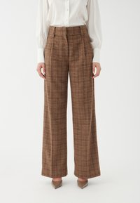 Braune Karohose mit weitem Bein, hoher Taille und gefaltetem Vorderteil. Der Stoff hat eine weiche, maßgeschneiderte Textur und zeigt ein klassisches Karomuster.