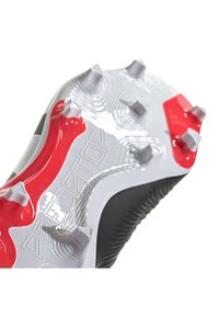 Suela de bota de fútbol Predator en negro y rojo, con tapones blancos y superficie texturizada con detalles de marca. La forma curva mejora el agarre.