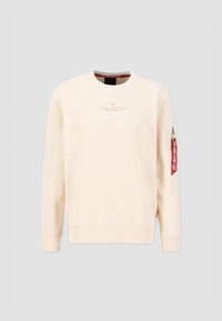 Beige Pullover aus weichem Stoff mit rundem Halsausschnitt, gerippten Bündchen und Saum. Verfügt über eine Reißverschlusstasche mit einem roten Etikett am Ärmel.