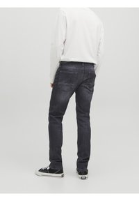 Mörka denimjeans med slim fit, med bakfickor och subtila sömnadsdetaljer, kombinerat med svarta och vita hög-top sneakers.