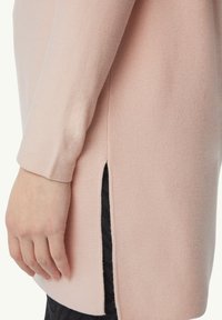 Long-sleeve, light pink sweater in soft knit fabric. Side slit detail reveals a black, textured underlayer. Simple, straight fit.