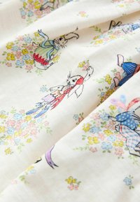 Katoenen stof met kleurrijke illustraties van konijnen in diverse kleding, omringd door kleine bloemetjes op een licht crèmekleurige achtergrond.