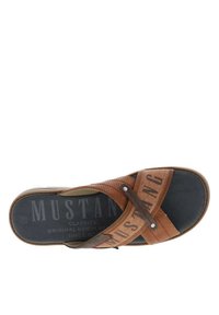 Sandale en tongs marron avec un design à bandes croisées, fabriquée en matériau texturé, dotée d'une semelle en caoutchouc grise et d'un nom de marque embossé sur la semelle intérieure.