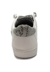 Sneaker bianco con finitura testurizzata, dotato di un tallone in pelle di serpente metallica e punta arrotondata. I lacci sono integrati nel design.