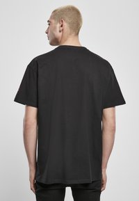 Černé bavlněné tričko s krátkými rukávy, volný střih a kulatým výstřihem. Nemá žádné viditelné vzory nebo kovové prvky.