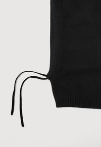 Sort strikket sweater med ribbede kanter og to lange bånd ved kanten. Materialet ser blødt og struktureret ud.
