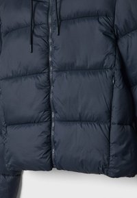 Veste matelassée bleu marine avec fermeture éclair à l'avant, deux poches latérales zippées et cordons au col.