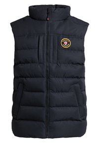 Gilet imbottito nero con colletto alto, chiusura a zip, tasche frontali e un patch circolare con una foglia d'acero e testo.