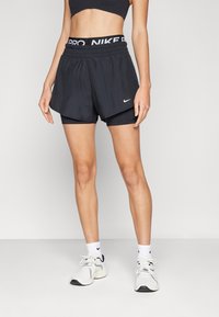 Mustat Nike-shortsit, joissa on joustava vyötärö, valkoisella "NIKE PRO" -tekstillä ja mustilla sisäshortseilla. Silkkinen kangas, väljä malli ilman kuvioita.