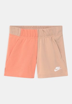 Tweekleurige Nike short met elastische tailleband, waarbij de linkerkant perzikkleurig is en de rechterkant beige, met een wit Nike-logo op het rechterbeen.