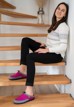 Purple and gray felt clogs with black soles, featuring a rounded toe and a backless design. Worn with black pants and a white patterned sweater.