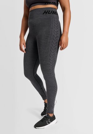 Grijze leggings met een hoge taille, voorzien van een gestructureerd patroon met chevronaccenten aan de zijkant en gecombineerd met zwarte sport schoenen.