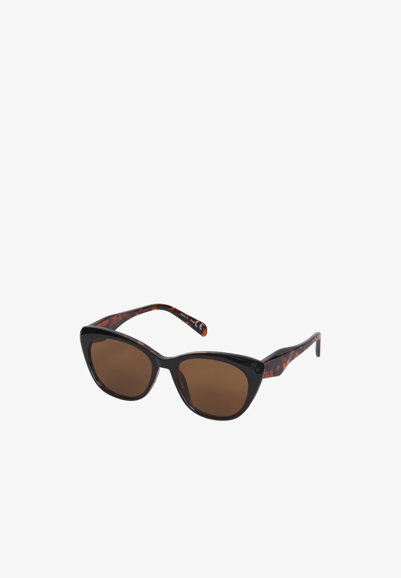 Lunettes de soleil noires style œil de chat avec verres marron et branches à motif écaille, inclinées sur un fond blanc.