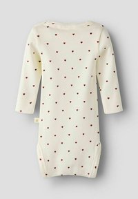 Kremowy kombinezon z długim rękawem, z wzorem małych czerwonych serc, wyeksponowany na jasnoszarym tle.