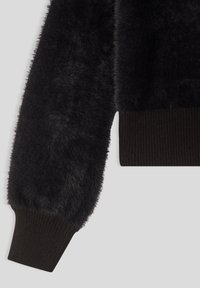 Czarny puszysty rękaw swetra o miękkiej teksturze; ściągacz w ciemnym brązie dodaje detalu i kontrastu.