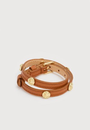 Brunt læderarmbånd med dobbelt omslag, dekoreret med guld cirkulære nitter og en guldbeslået spænde på hvid baggrund.