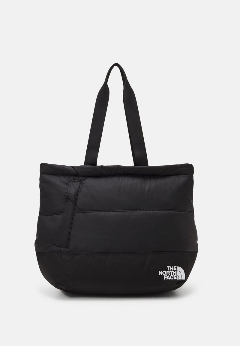 Sac cabas noir matelassé avec larges poignées et logo The North Face blanc dans le coin inférieur droit sur un fond uni.