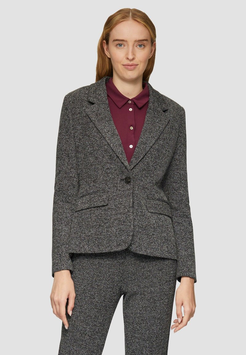 Blazer grigio a motivo houndstooth con due tasche frontali, chiusura a un bottone e forma leggermente aderente, abbinato a una camicia a colletto color bordeaux.