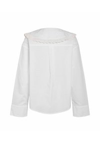 Biała koszula z długim rękawem, z obłym kołnierzykiem ozdobionym różową koronką w kształcie falbanek, mankiety zapinane na guziki oraz luźny krój.