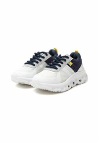 Zapatillas de malla y tela en blanco y marino, con suelas gruesas, acentos texturizados, cordones redondos y una lengüeta trasera amarilla para facilitar su uso.