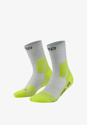 Pair of mid-calf gray socks with neon yellow cushioning on toes, heels, and sides, featuring a black logo near the top and sole.