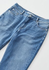 Jeans en denim bleu clair avec un design classique à cinq poches, bouton en argent et surpiqûres contrastées. Texture lisse avec un léger délavage.